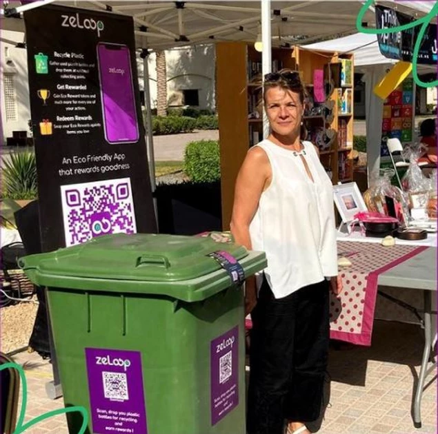 Lady standing beside recycling bin with ZeLoop QR code